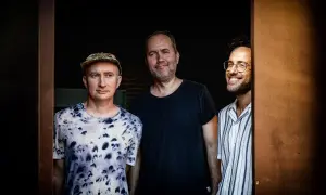 Trzech mężczyzn, muzycy, gotowi do improwizacji w ekspresyjnym stylu jazzowym.