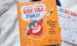 Pomarańczowa książka "Bądź sobą, Pinku!" z jeżem i zającem. Obok planer tygodniowy.