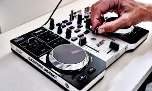 Dłoń DJ-a miksuje utwory na kontrolerze Hercules DJControl Instinct, tworząc energiczną muzykę do tańca.