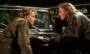 Dwóch mężczyzn w skórzanych kurtkach pochyla się nad maską samochodu. Scena z filmu o mafii, pełna napięcia.