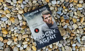 Okładka książki "Nocny agent" Matthew Quirka leży na kamieniach. Bohaterowie się nie rodzą, odpowiadają na wezwanie.