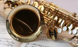Złoty saksofon leży na nutach, gotowy do zagrania piosenek jazzowych.