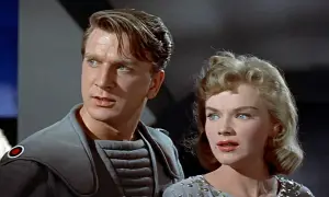 Leslie Nielsen w futurystycznym stroju obok kobiety w ozdobnej sukni, scena z jednego z jego filmów lub seriali.