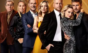Grupa osób pozuje do zdjęcia. Widać tu fuks 2 obsada: starszego mężczyznę w brązowej marynarce, dwie kobiety w eleganckich sukniach i trzech mężczyzn w garniturach.