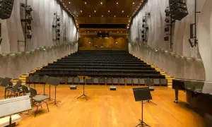 Pusta sala kameralna NOSPR z rzędami czarnych foteli, fortepianem i pulpitami dla muzyków.
