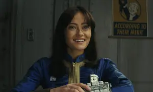 Uśmiechnięta Lucy z serialu Fallout, w niebieskim kombinezonie, trzymająca urządzenie. Na ścianie wisi plakat "According to their merit".