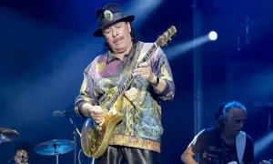 Carlos Santana gra na złotej gitarze, przypominając dźwięki swojego najbardziej znanego utworu.