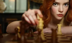 Beth Harmon, bohaterka "Gambitu królowej 2", skupiona na szachownicy, wykonuje ruch.