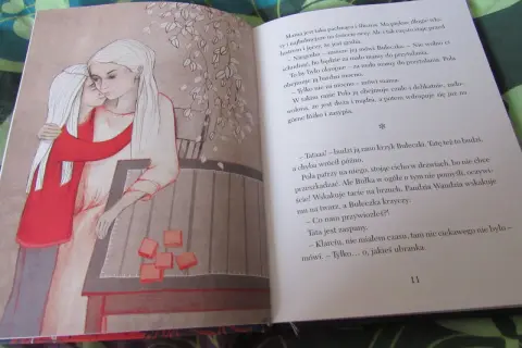 Wiłka smocza dziewczynka przytula mamę. Obok na stole leżą pomarańczowe kostki.