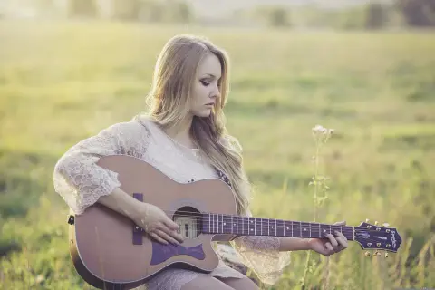 Dziewczyna gra na gitarze, tworząc własne, najsłynniejsze riffy gitarowe w otoczeniu natury.