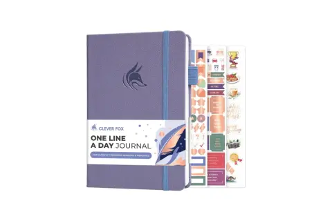 Fioletowy dziennik "One Line A Day Journal" z logo sprytnej kuny i zestawem motywacyjnych naklejek.