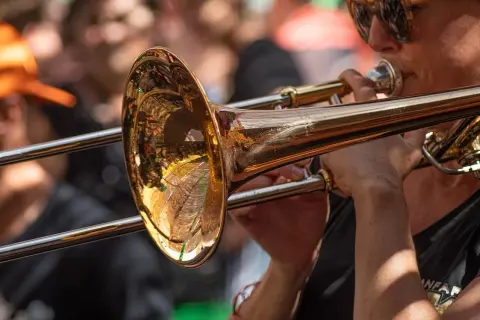 Muzyk w okularach gra na puzonie, tworząc dźwięki w stylu jazzowym.
