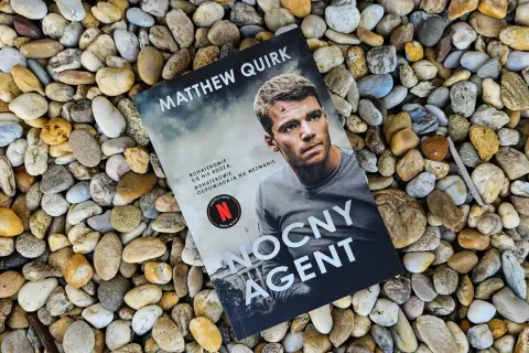Okładka książki "Nocny agent" Matthew Quirka leży na kamieniach. Bohaterowie się nie rodzą, odpowiadają na wezwanie.