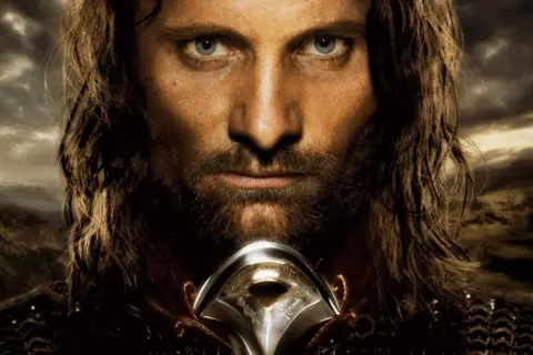 Viggo Mortensen jako Aragorn, zamyślony, z mieczem u szyi, na tle burzowego nieba i gór.