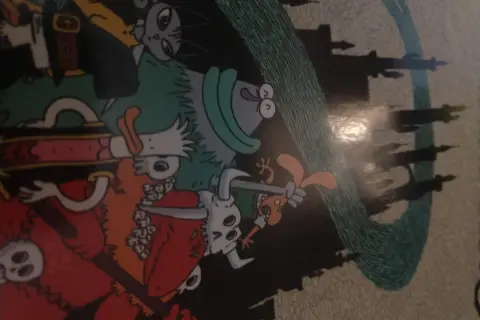 Kolorowy komiks z postaciami w stylu fantasy, przypominającymi bohaterów gry o nazwie "dożon". W tle widać zarys zamku.