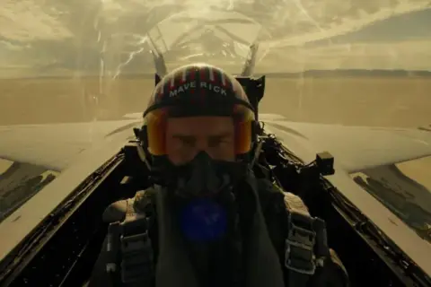 Pilot w hełmie "Maverick" w kokpicie myśliwca, gotowy do akcji. Scena jak z najlepszych filmów o lotnictwie.