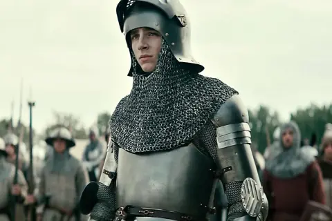 Młody rycerz w zbroi, gotowy do bitwy. Scena z filmów o średniowieczu, gdzie historia ożywa na ekranie.