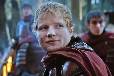Ed Sheeran w stroju rycerza, jakby z planu "Gra o Tron", z towarzyszami w tle.
