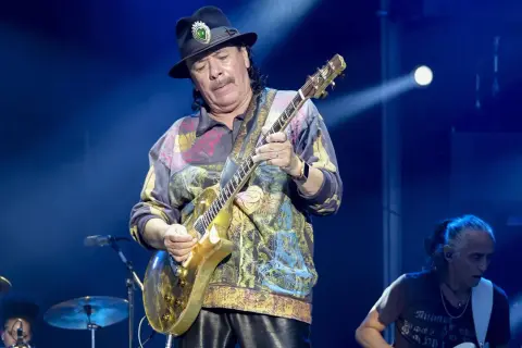 Carlos Santana gra na złotej gitarze, przypominając dźwięki swojego najbardziej znanego utworu.