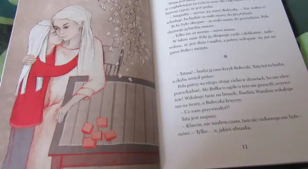 Wiłka smocza dziewczynka przytula mamę. Obok na stole leżą pomarańczowe kostki.