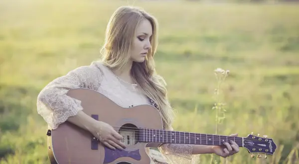 Dziewczyna gra na gitarze, tworząc własne, najsłynniejsze riffy gitarowe w otoczeniu natury.