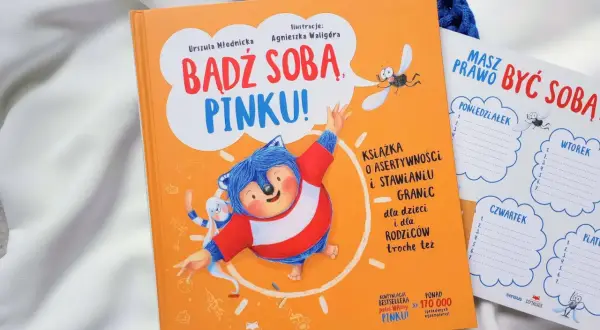Pomarańczowa książka "Bądź sobą, Pinku!" z jeżem i zającem. Obok planer tygodniowy.