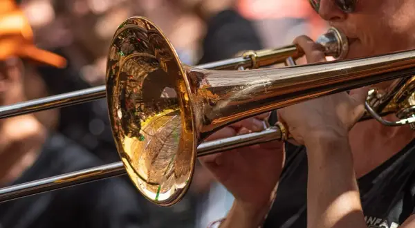 Muzyk w okularach gra na puzonie, tworząc dźwięki w stylu jazzowym.