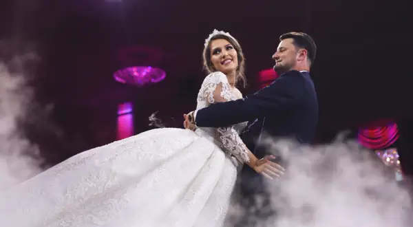 Para młoda tańczy w dymie. Ona w sukni ślubnej, on w garniturze. Idealny moment na rockowe piosenki na wesele.