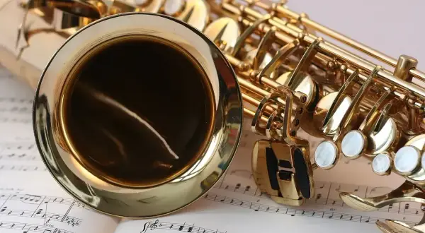 Złoty saksofon leży na nutach, gotowy do zagrania piosenek jazzowych.