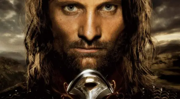 Viggo Mortensen jako Aragorn, zamyślony, z mieczem u szyi, na tle burzowego nieba i gór.