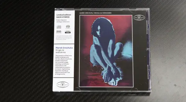 Okładka płyty SACD Marka Grechuty "Droga za widnokres". Stylizowana postać w odcieniach niebieskiego na czerwonym tle, przypomina taniec.