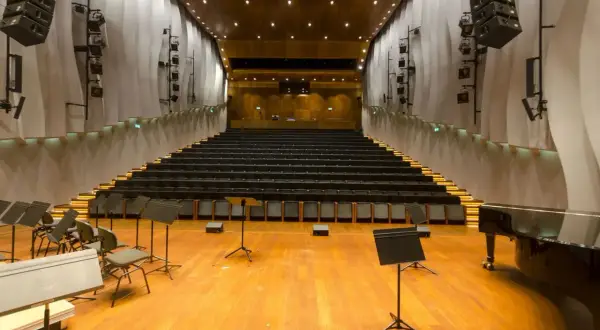 Pusta sala kameralna NOSPR z rzędami czarnych foteli, fortepianem i pulpitami dla muzyków.