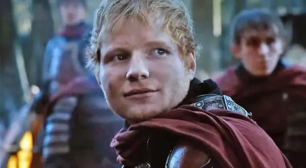 Ed Sheeran w stroju rycerza, jakby z planu "Gra o Tron", z towarzyszami w tle.