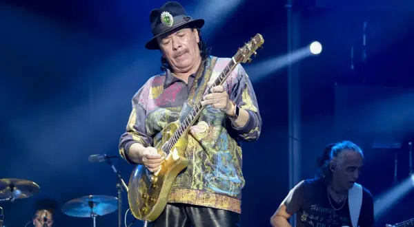 Carlos Santana gra na złotej gitarze, przypominając dźwięki swojego najbardziej znanego utworu.