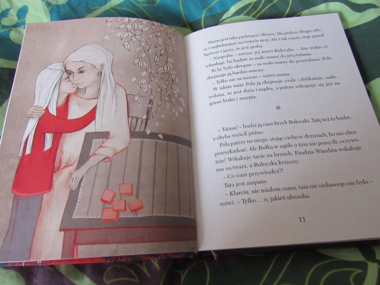 Wiłka smocza dziewczynka przytula mamę. Obok na stole leżą pomarańczowe kostki.