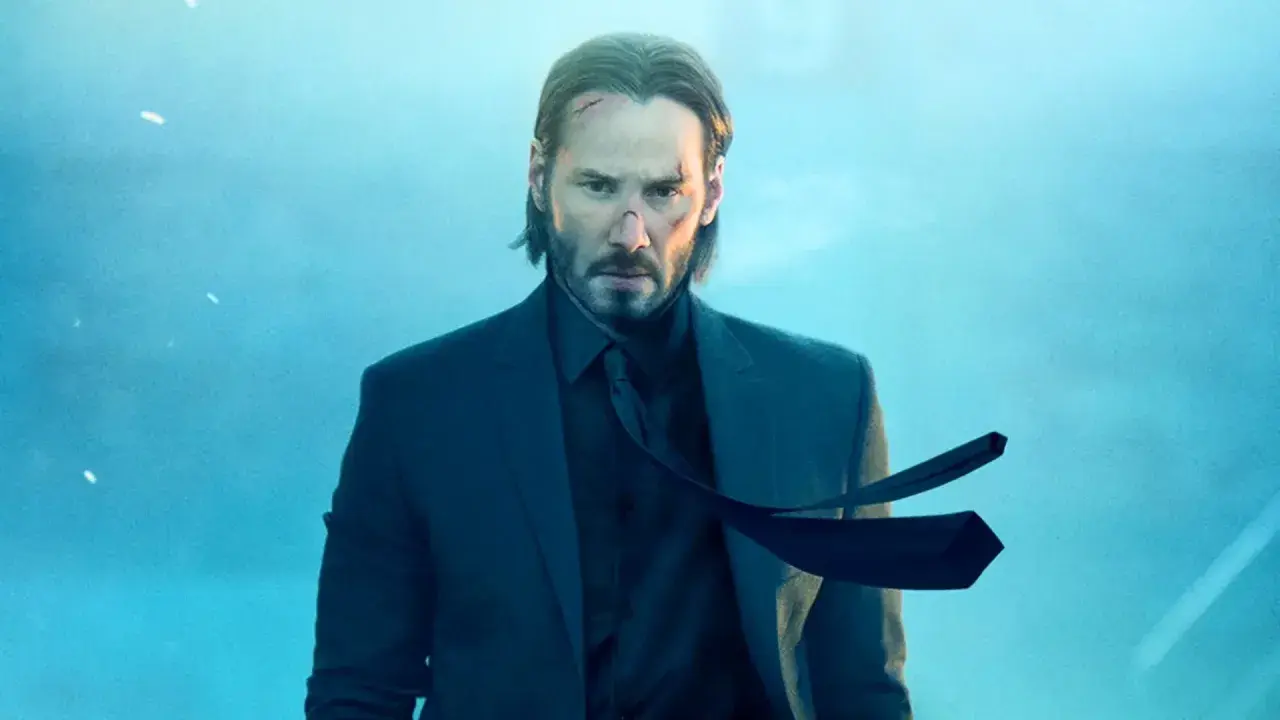 John Wick, z bliznami na twarzy, w garniturze, czeka na premierę John Wick 5.