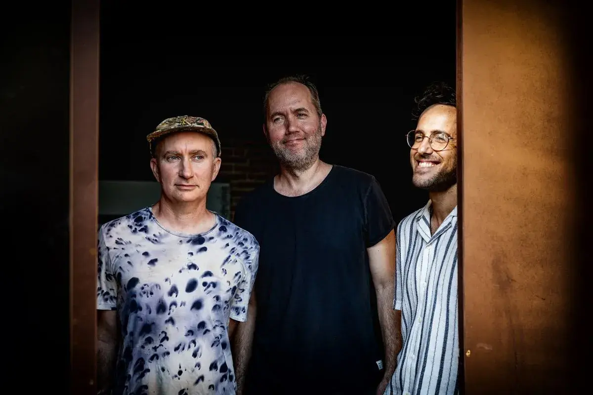 Trzech mężczyzn, muzycy, gotowi do improwizacji w ekspresyjnym stylu jazzowym.