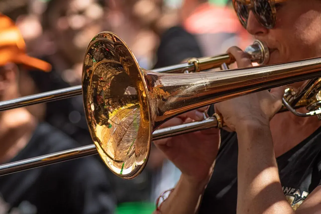 Muzyk w okularach gra na puzonie, tworząc dźwięki w stylu jazzowym.