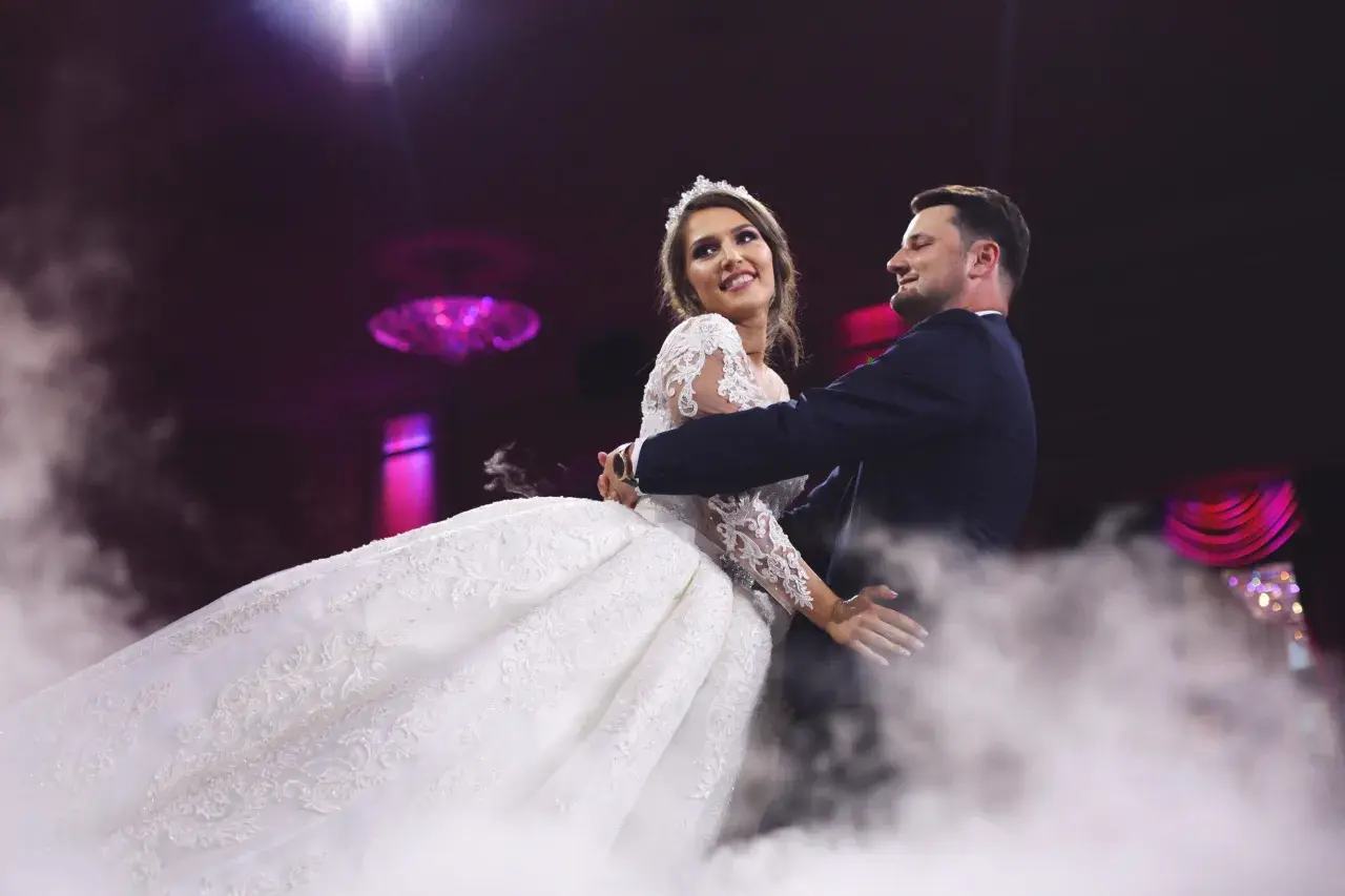 Para młoda tańczy w dymie. Ona w sukni ślubnej, on w garniturze. Idealny moment na rockowe piosenki na wesele.