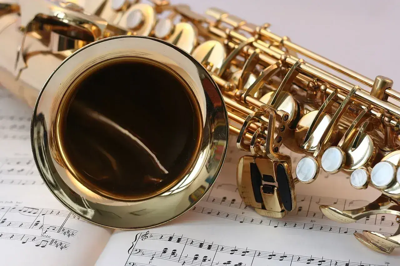 Złoty saksofon leży na nutach, gotowy do zagrania piosenek jazzowych.