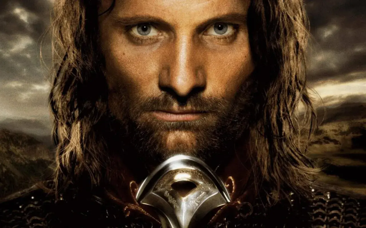 Viggo Mortensen jako Aragorn, zamyślony, z mieczem u szyi, na tle burzowego nieba i gór.
