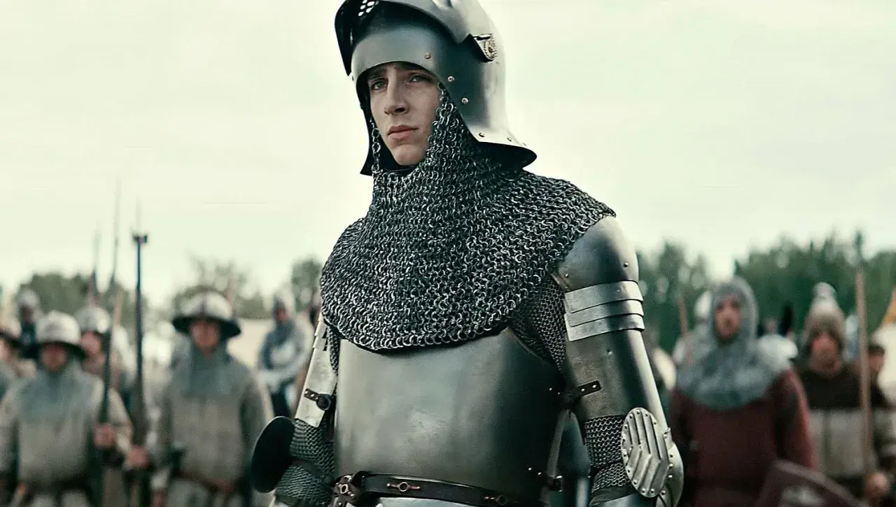 Młody rycerz w zbroi, gotowy do bitwy. Scena z filmów o średniowieczu, gdzie historia ożywa na ekranie.