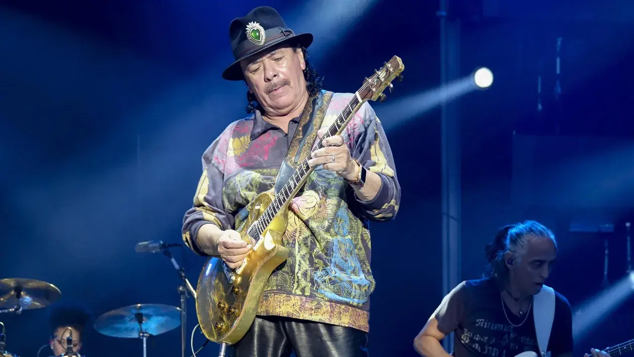 Carlos Santana gra na złotej gitarze, przypominając dźwięki swojego najbardziej znanego utworu.