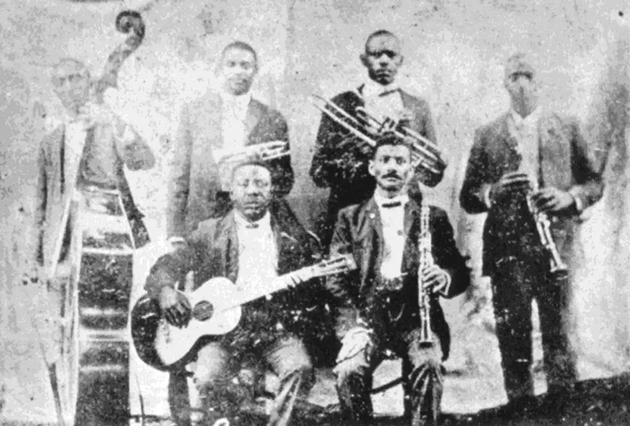 Zespół muzyków grający muzykę jazzową: kontrabasista, gitarzysta, trębacz i klarnecista.