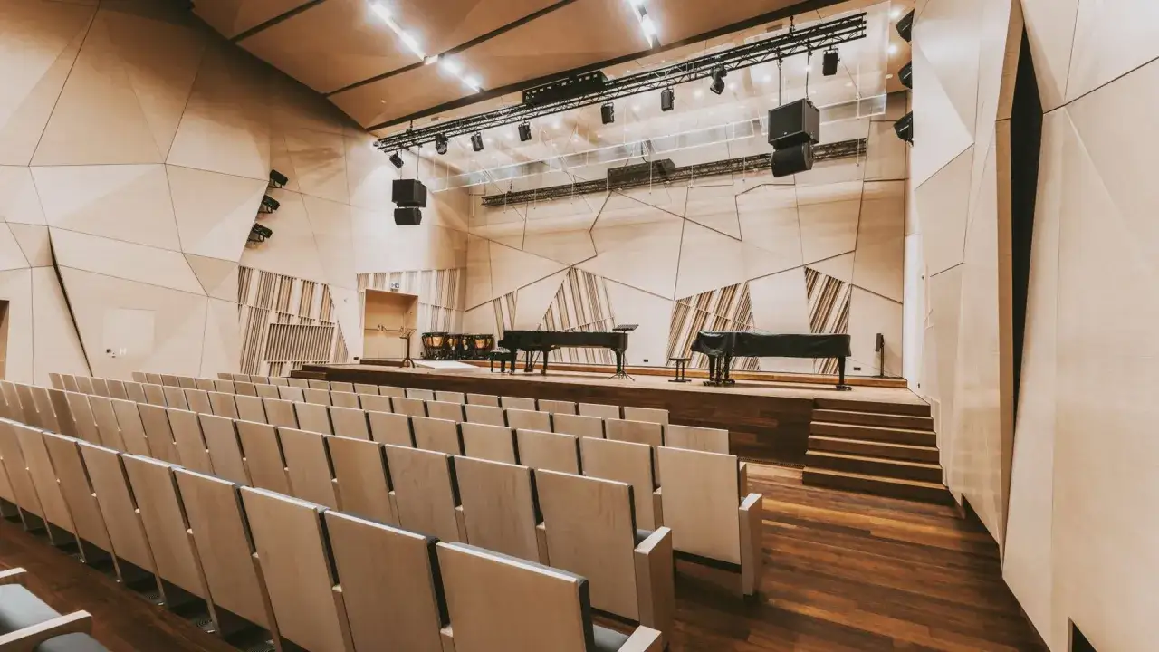 Nowe sale koncertowe czekają na muzyków. Na scenie fortepiany i kotły, przed nią rzędy pustych krzeseł.