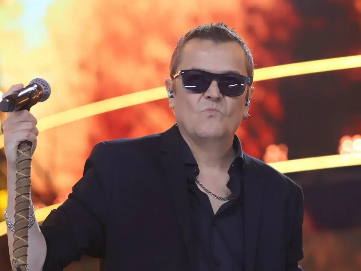 Artysta w okularach przeciwsłonecznych, z mikrofonem w dłoni, jakby śpiewał o wilkach dwóch siostrach.