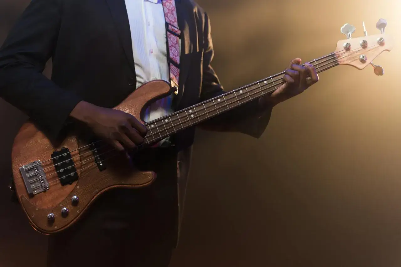Muzyk w garniturze gra na basie, tworząc niepowtarzalne brzmienie. To gitara jazzowa inaczej, pełna pasji i rytmu.