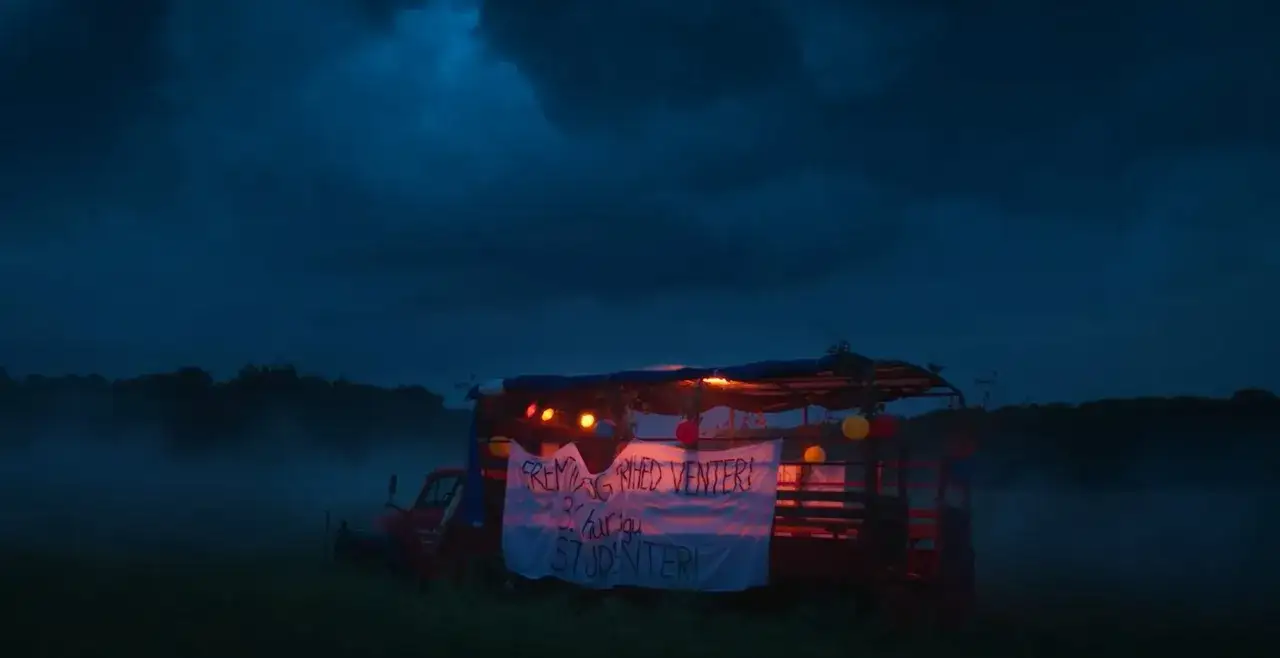 Nocny krajobraz z ciężarówką udekorowaną lampkami i banerem