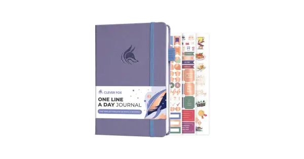 Fioletowy dziennik "One Line A Day Journal" z logo sprytnej kuny i zestawem motywacyjnych naklejek.