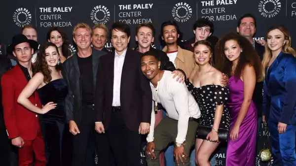 Uśmiechnięta cobra kai obsada pozuje do zdjęcia na tle logo The Paley Center for Media.
